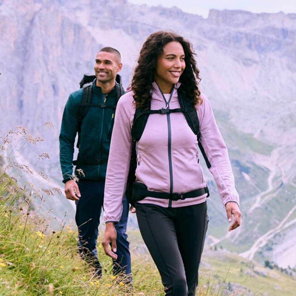 Zwei Wanderer mit Rucksäcken auf einem Bergpfad vor felsiger Berglandschaft